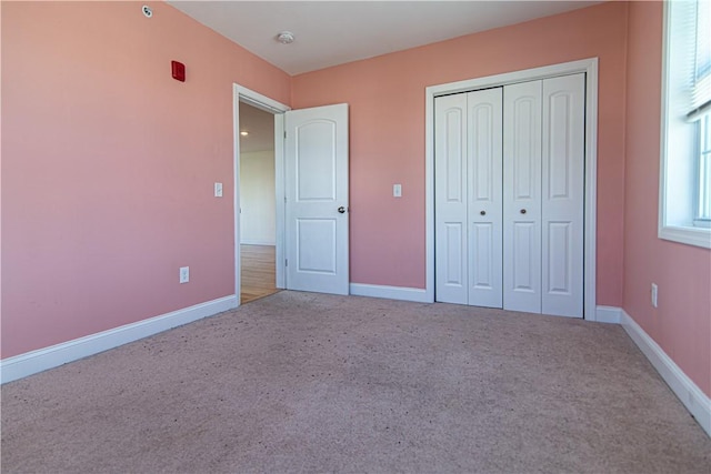 unfurnished bedroom featuring a closet, carpet flooring, and baseboards