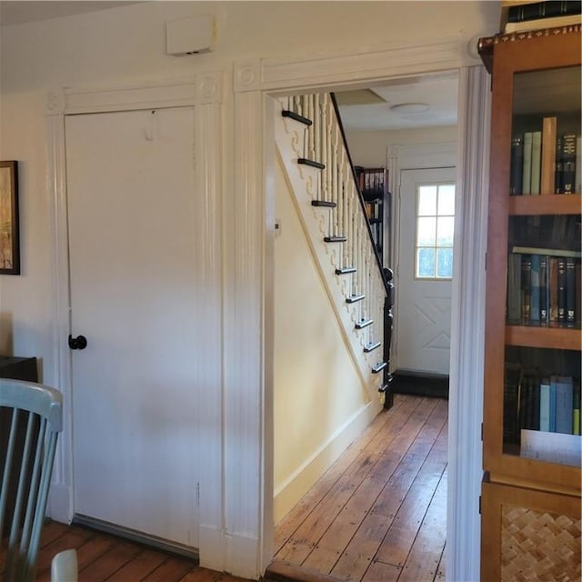 foyer entrance featuring stairs, wood-type flooring, and baseboards