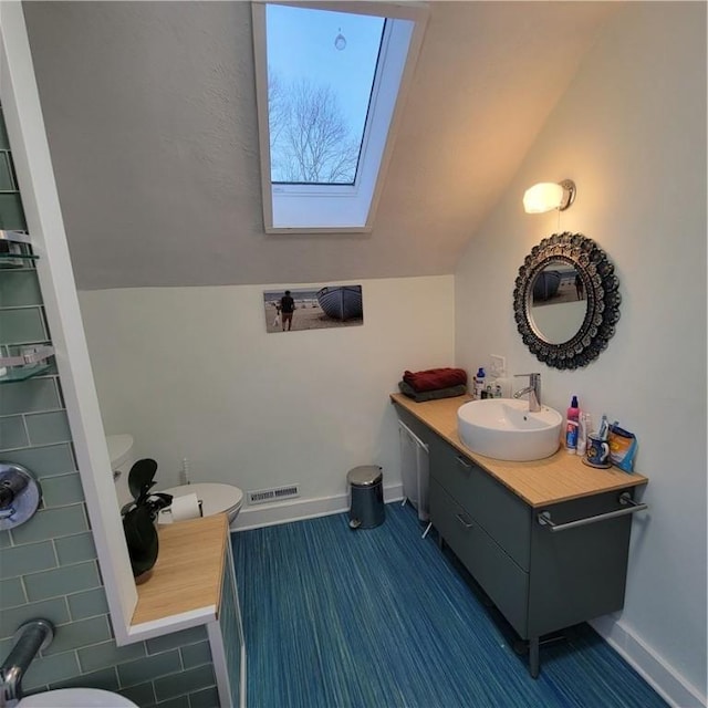 bathroom with toilet, lofted ceiling with skylight, baseboards, and visible vents