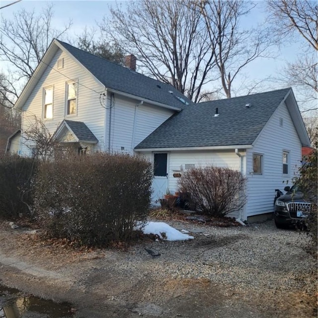 view of side of property featuring a chimney and roof with shingles