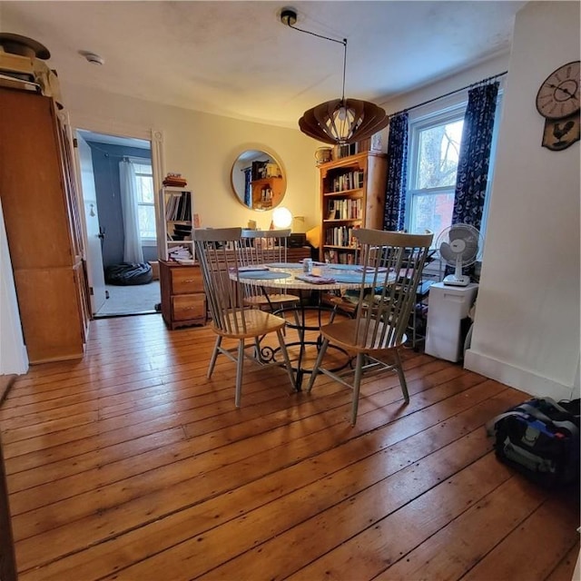 dining room featuring wood-type flooring, a healthy amount of sunlight, and baseboards