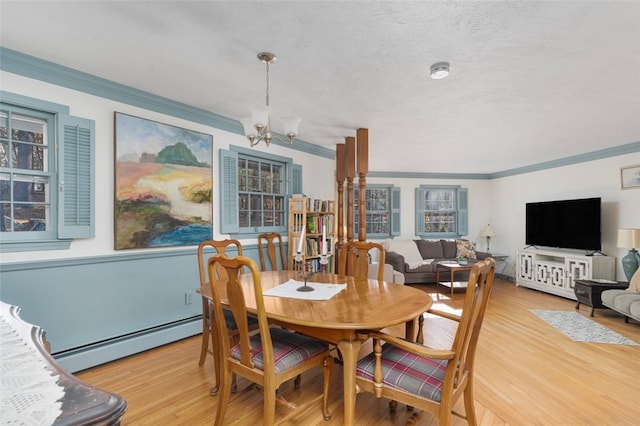 dining room featuring a notable chandelier, a baseboard heating unit, ornamental molding, a textured ceiling, and light wood-type flooring