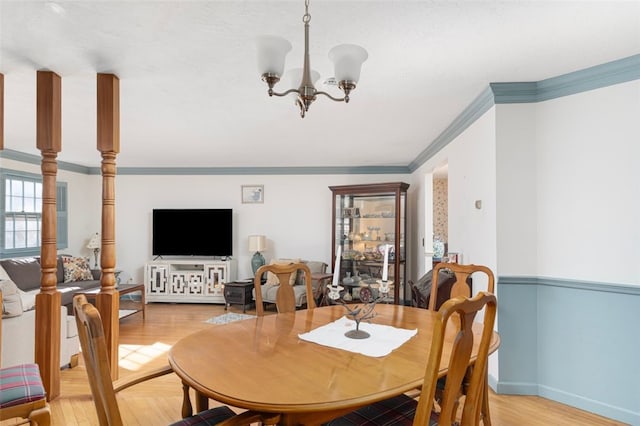 dining area featuring light wood-type flooring, an inviting chandelier, baseboards, and ornamental molding