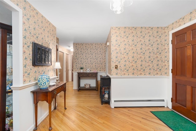 entrance foyer with light wood-type flooring, baseboard heating, wainscoting, and wallpapered walls