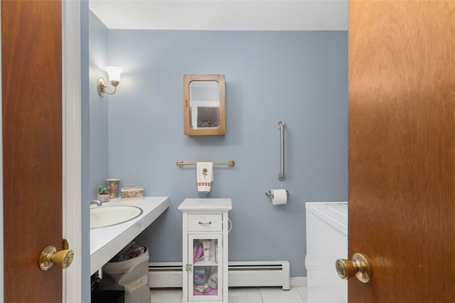 bathroom with toilet, tile patterned flooring, baseboard heating, and a sink