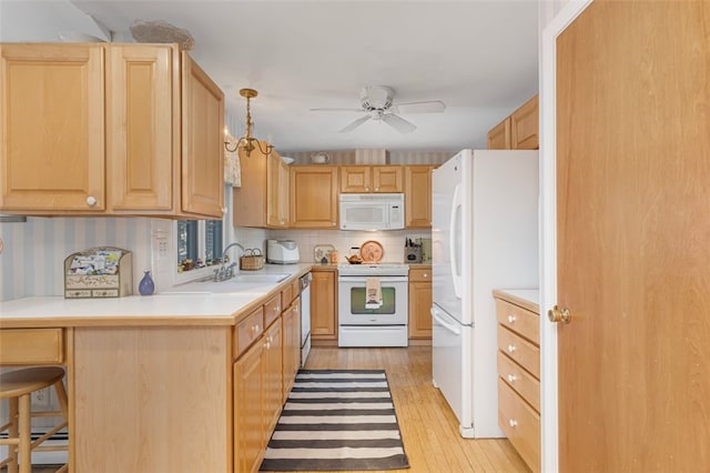 kitchen featuring white appliances, a sink, and light brown cabinetry