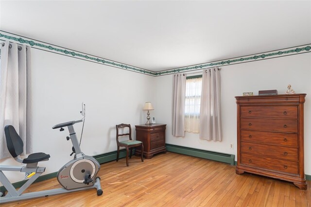 workout area featuring light wood-style floors and a baseboard heating unit