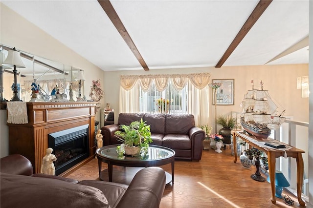 living room with a glass covered fireplace, wood finished floors, and beamed ceiling