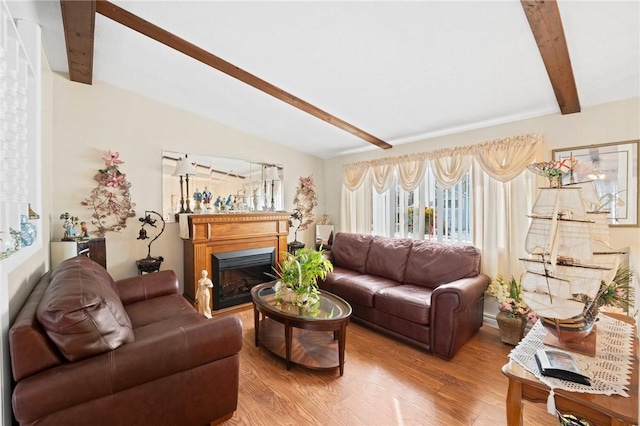 living room with vaulted ceiling with beams, light wood finished floors, and a fireplace