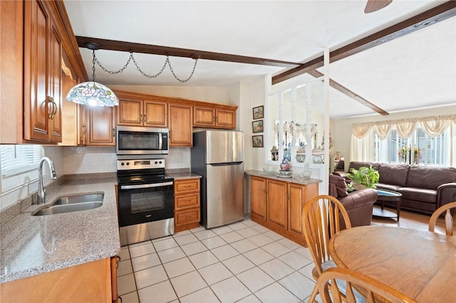 kitchen featuring brown cabinetry, appliances with stainless steel finishes, open floor plan, vaulted ceiling with beams, and a sink