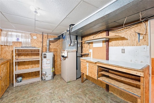 basement featuring a drop ceiling, gas water heater, and heating unit