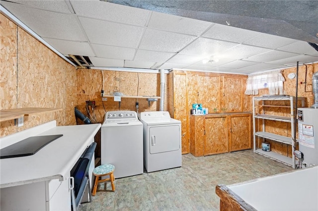 clothes washing area featuring laundry area, gas water heater, washing machine and clothes dryer, and wooden walls