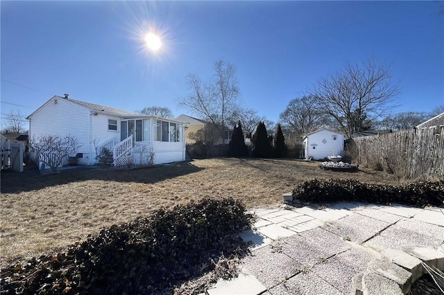 view of yard with an outbuilding, fence, a sunroom, and entry steps