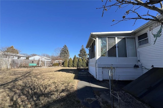 view of home's exterior featuring fence and a sunroom