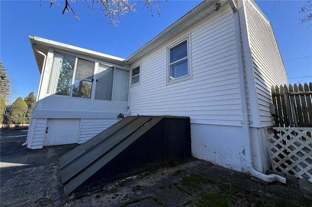 view of side of home featuring a garage and fence