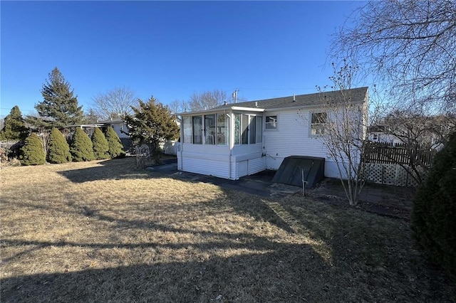 rear view of house featuring a sunroom and a yard