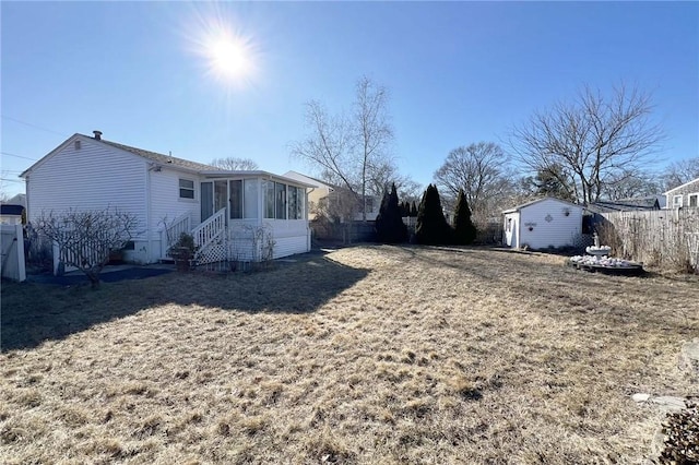 view of yard featuring entry steps, an outdoor structure, fence, and a sunroom