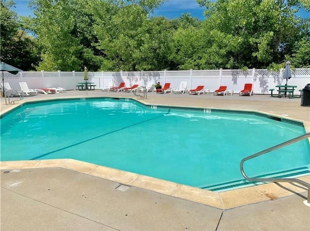 community pool with a patio area and fence