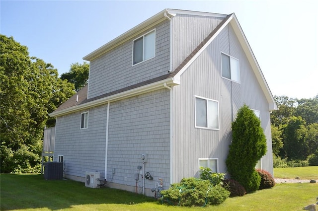 view of side of property with central AC, a lawn, and ac unit