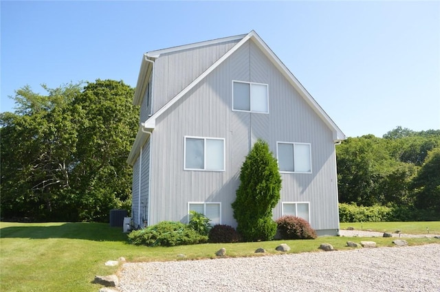 view of side of home featuring cooling unit and a yard