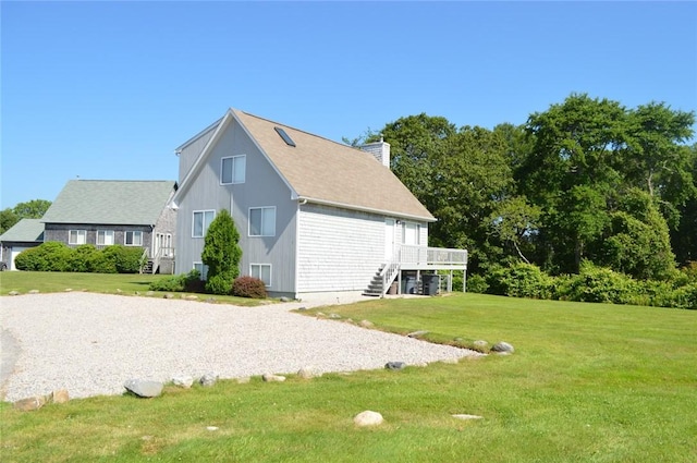 view of property exterior featuring a chimney, stairway, a deck, and a lawn