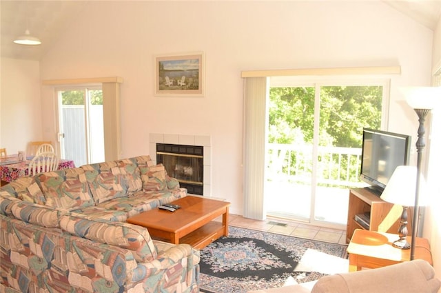 tiled living room featuring vaulted ceiling and a tiled fireplace