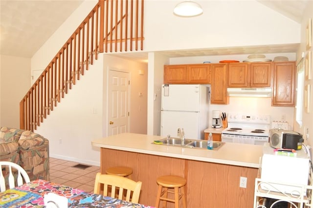 kitchen with white appliances, light tile patterned floors, a breakfast bar area, under cabinet range hood, and a sink