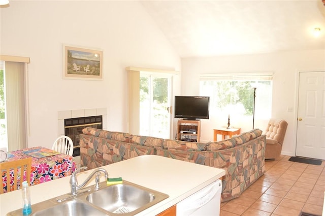 kitchen with a fireplace, light tile patterned floors, open floor plan, a sink, and dishwasher