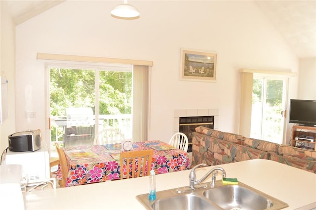 kitchen featuring plenty of natural light, a tiled fireplace, vaulted ceiling, and a sink