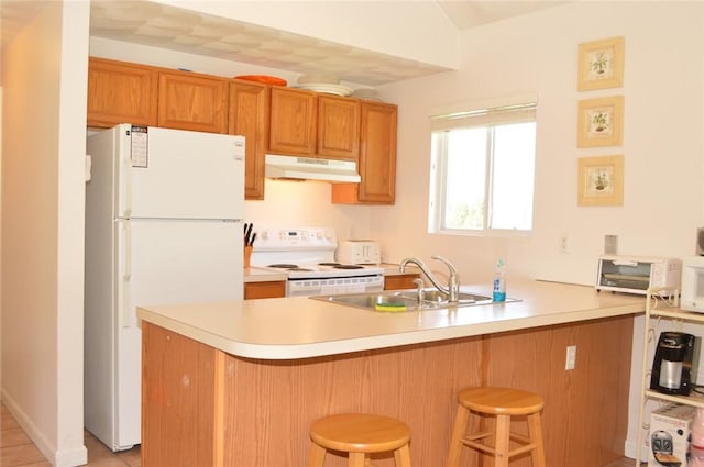 kitchen with white appliances, a peninsula, under cabinet range hood, a kitchen bar, and a sink