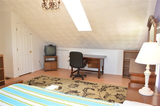 office area featuring vaulted ceiling with skylight, wood finished floors, and baseboards