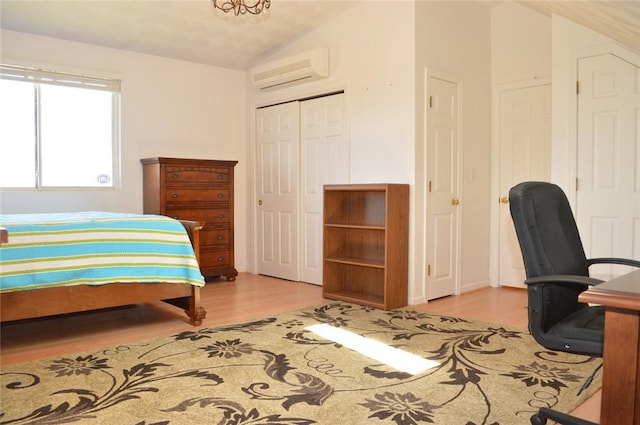 bedroom with a wall unit AC, a closet, vaulted ceiling, and wood finished floors