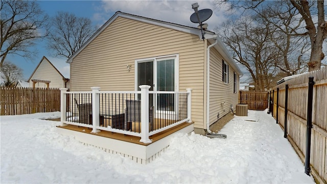 snow covered back of property with a fenced backyard