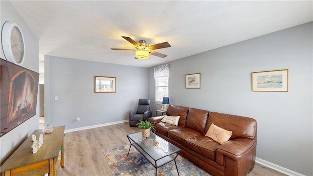 living area with baseboards, ceiling fan, and light wood finished floors