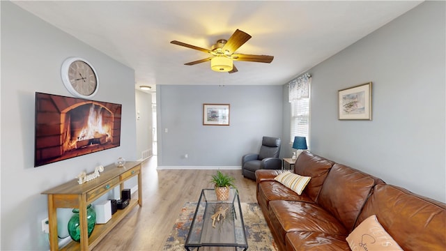 living room with ceiling fan, wood finished floors, visible vents, and baseboards