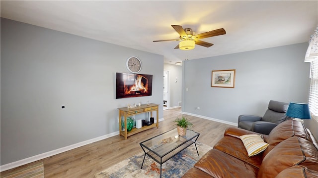 living area with light wood-type flooring, ceiling fan, and baseboards