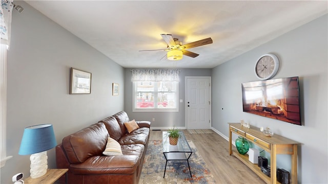 living area with light wood-type flooring, ceiling fan, and baseboards