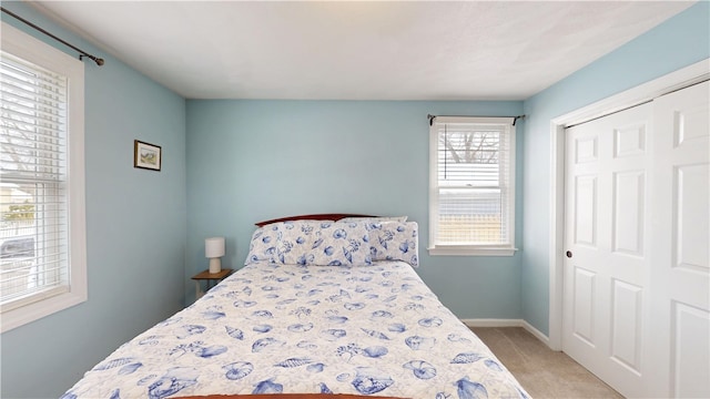 bedroom featuring a closet, light carpet, and baseboards