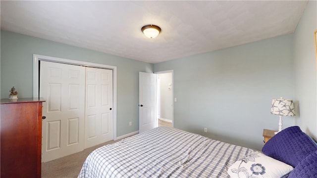 carpeted bedroom with a closet and baseboards