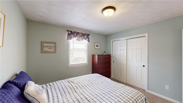 carpeted bedroom featuring baseboards and a closet