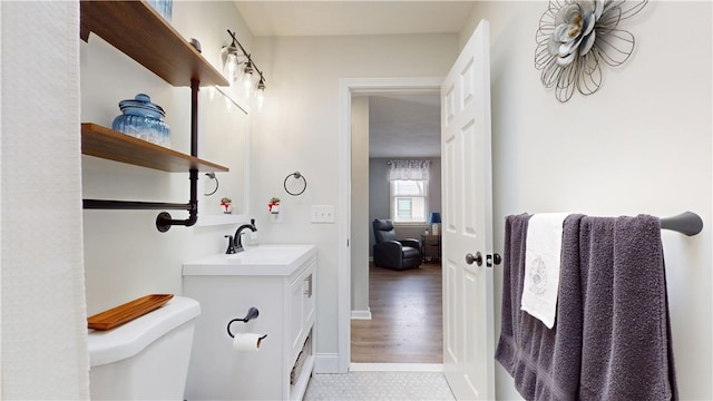 bathroom featuring baseboards, vanity, and toilet