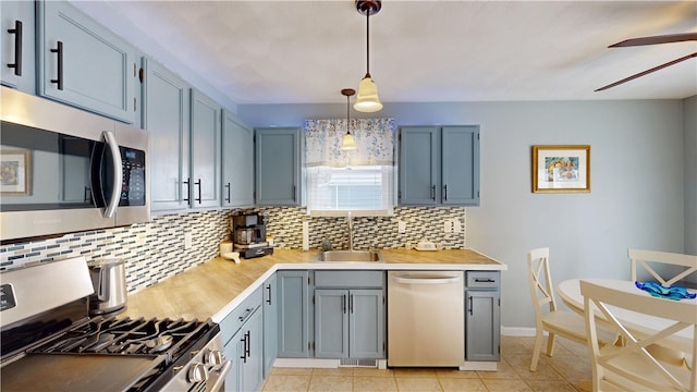 kitchen with decorative backsplash, ceiling fan, appliances with stainless steel finishes, light countertops, and a sink