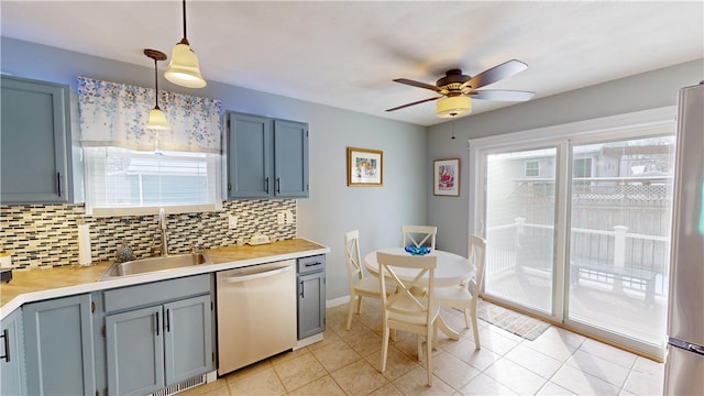 kitchen with a sink, hanging light fixtures, light countertops, appliances with stainless steel finishes, and backsplash