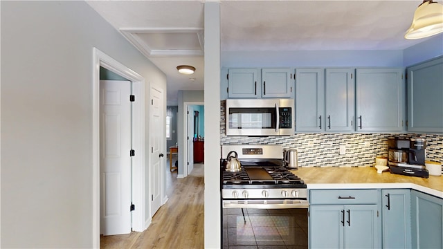 kitchen with stainless steel appliances, tasteful backsplash, light countertops, blue cabinets, and light wood-type flooring