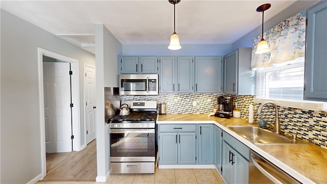 kitchen featuring decorative backsplash, appliances with stainless steel finishes, hanging light fixtures, light countertops, and a sink