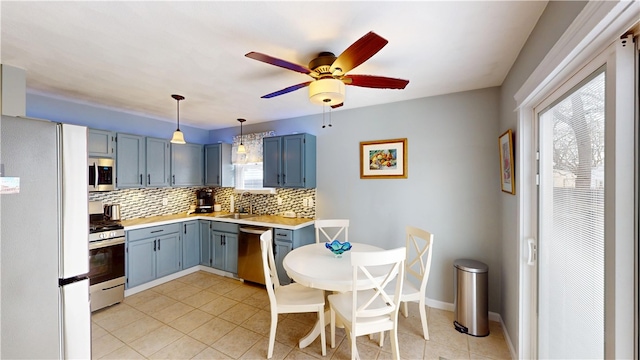 kitchen featuring tasteful backsplash, appliances with stainless steel finishes, blue cabinets, light countertops, and a sink