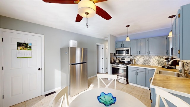 kitchen with appliances with stainless steel finishes, backsplash, a sink, and light tile patterned flooring