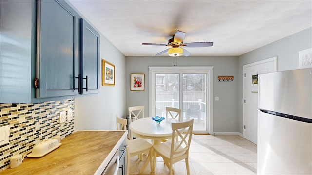 dining room with light tile patterned floors, a ceiling fan, and baseboards