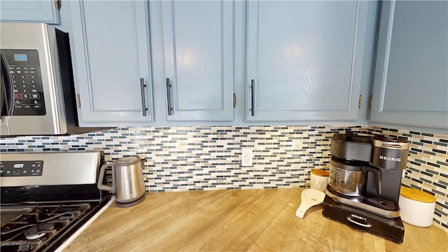 kitchen featuring light countertops, appliances with stainless steel finishes, wood finished floors, and decorative backsplash