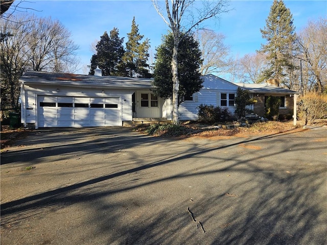 ranch-style house featuring aphalt driveway, a chimney, and an attached garage